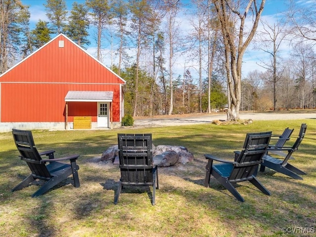 view of yard featuring a pole building, an outdoor structure, and a fire pit