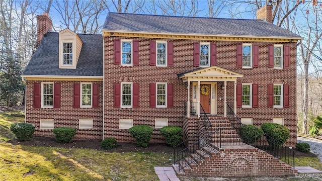 colonial house featuring crawl space, a chimney, and brick siding