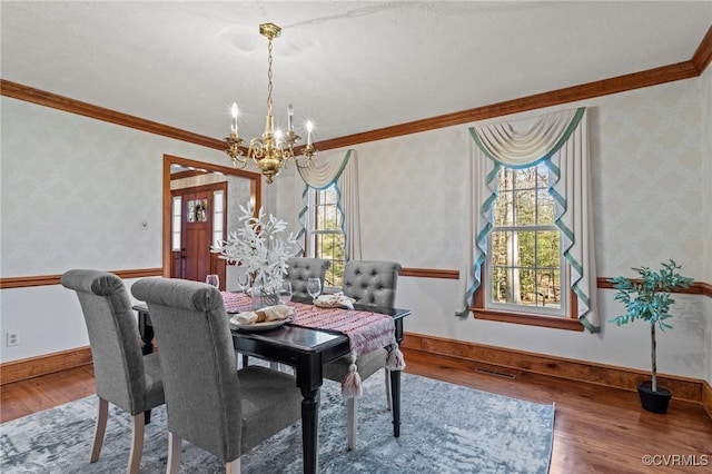 dining space featuring hardwood / wood-style flooring, crown molding, and wallpapered walls