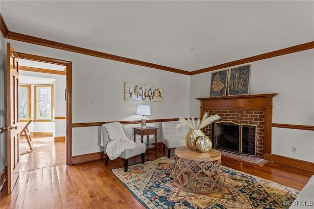 living area featuring a brick fireplace, wood-type flooring, and crown molding