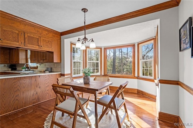 dining space with baseboards, hardwood / wood-style floors, crown molding, a textured ceiling, and a chandelier