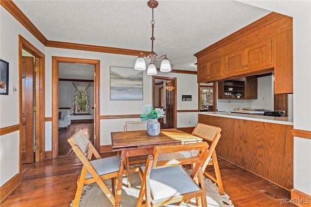 dining area with a chandelier, dark wood-type flooring, baseboards, and crown molding