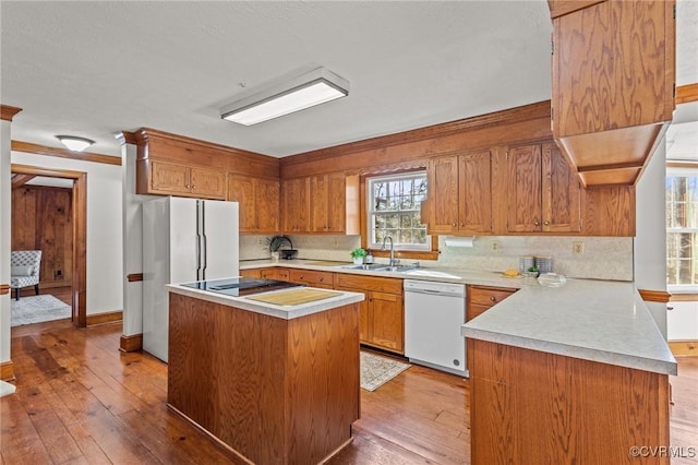 kitchen featuring white appliances, light countertops, a sink, and light wood finished floors