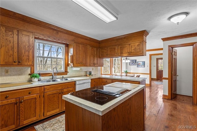 kitchen with dishwasher, brown cabinetry, plenty of natural light, and a sink