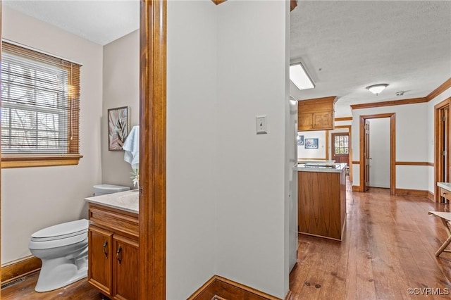 interior space featuring hardwood / wood-style floors, baseboards, vanity, and toilet