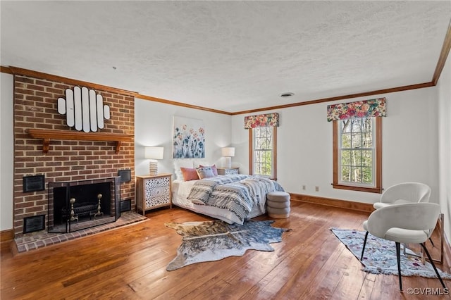 bedroom with crown molding, a fireplace, hardwood / wood-style floors, a textured ceiling, and baseboards