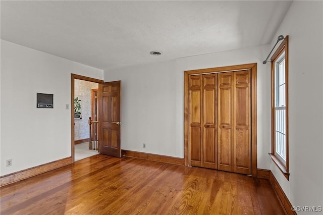 unfurnished bedroom featuring wood finished floors, visible vents, and baseboards