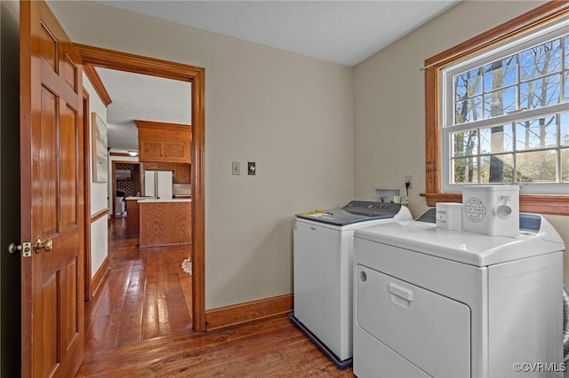 clothes washing area featuring laundry area, baseboards, independent washer and dryer, and hardwood / wood-style floors