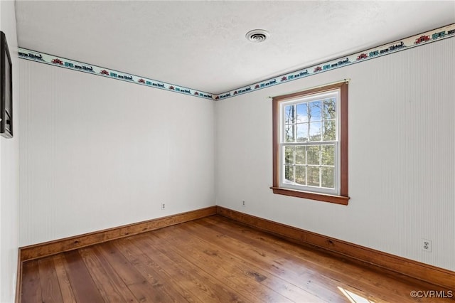 spare room with baseboards, visible vents, and hardwood / wood-style floors