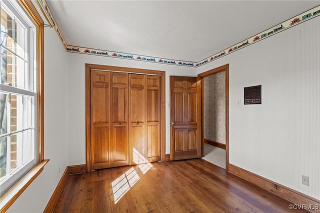 unfurnished bedroom featuring a closet, baseboards, and dark wood-style flooring