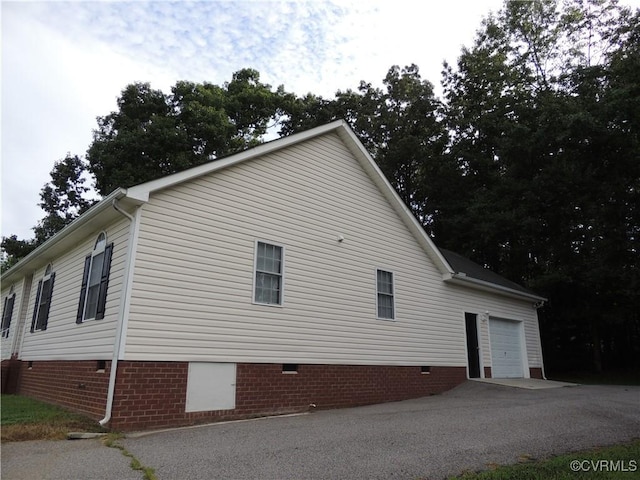 view of side of home with a garage, crawl space, and driveway