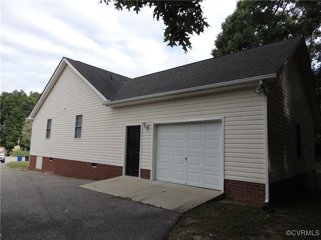 exterior space featuring crawl space, a garage, aphalt driveway, and roof with shingles