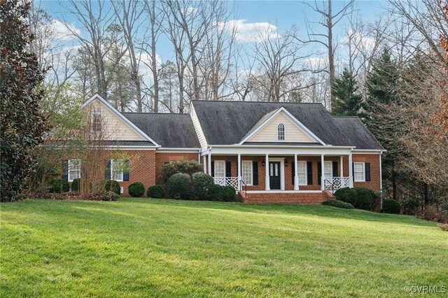 view of front of house with a porch, a front yard, and brick siding