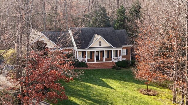 view of front facade with a porch, a front lawn, and brick siding