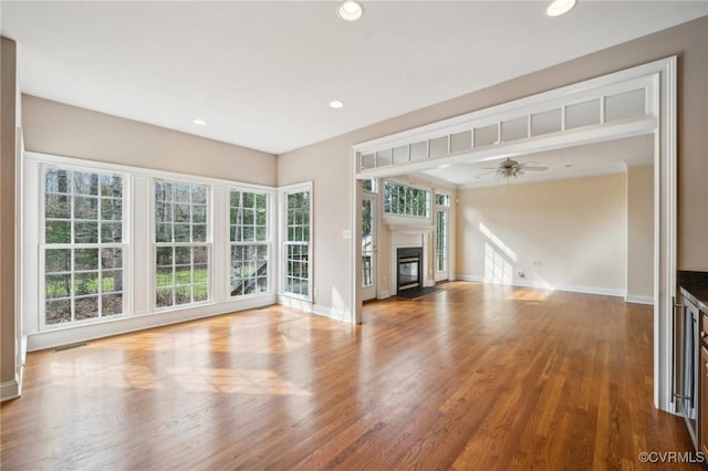 unfurnished living room featuring recessed lighting, wood finished floors, a fireplace with flush hearth, visible vents, and baseboards