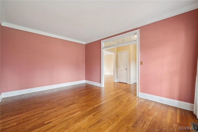 unfurnished room featuring baseboards, wood finished floors, and crown molding