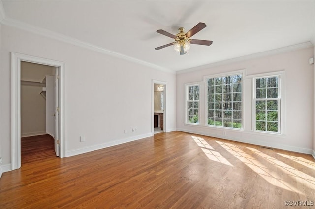 spare room with ornamental molding, wood finished floors, and baseboards