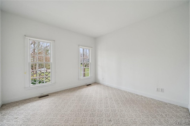 empty room with carpet flooring, visible vents, and baseboards