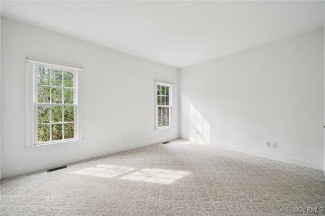 carpeted empty room featuring visible vents and baseboards