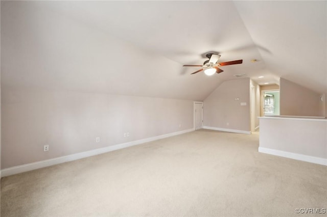 additional living space featuring a ceiling fan, light colored carpet, vaulted ceiling, and baseboards