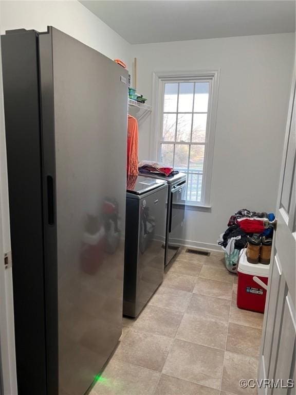 laundry area with laundry area, washing machine and dryer, and visible vents