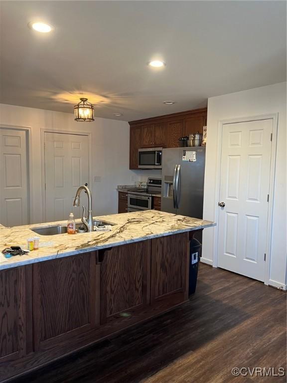 kitchen featuring a sink, dark wood-style floors, recessed lighting, stainless steel appliances, and light stone countertops