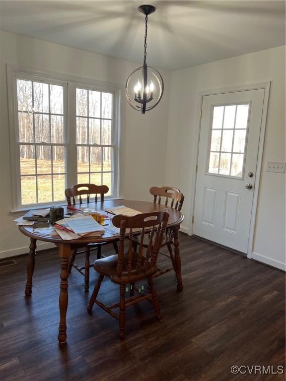 dining area featuring dark wood-style floors, an inviting chandelier, and baseboards