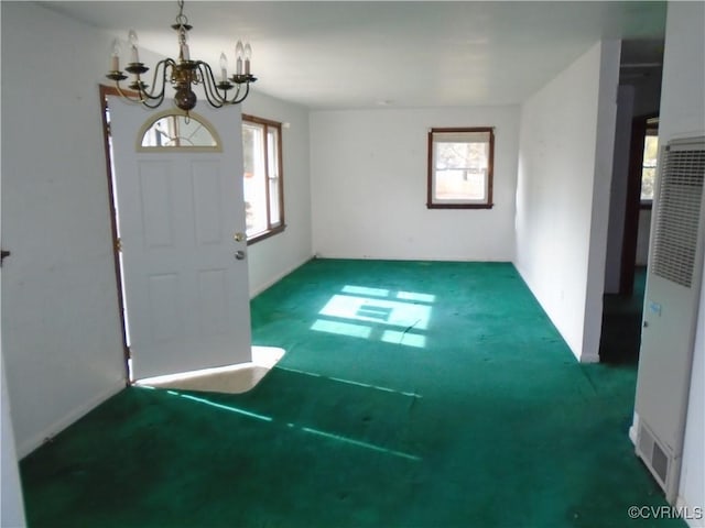 carpeted foyer with a heating unit and an inviting chandelier