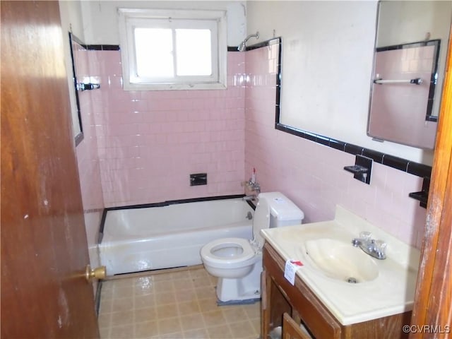 bathroom with shower / tub combination, toilet, vanity, tile walls, and wainscoting