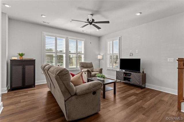 living area featuring a healthy amount of sunlight, visible vents, baseboards, and wood finished floors