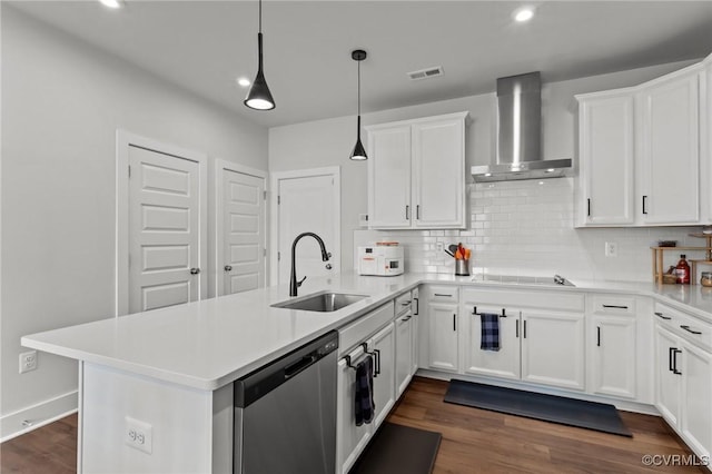 kitchen featuring visible vents, dishwasher, wall chimney exhaust hood, a peninsula, and a sink