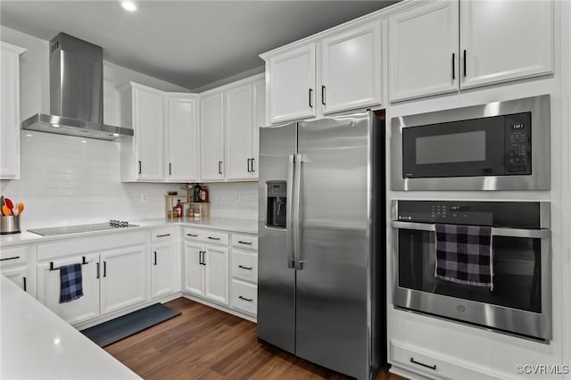 kitchen with dark wood-style floors, light countertops, appliances with stainless steel finishes, white cabinets, and wall chimney exhaust hood