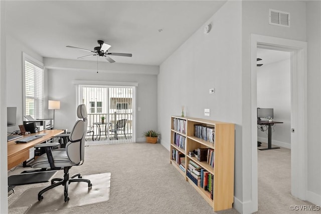 carpeted home office featuring a ceiling fan, visible vents, and baseboards