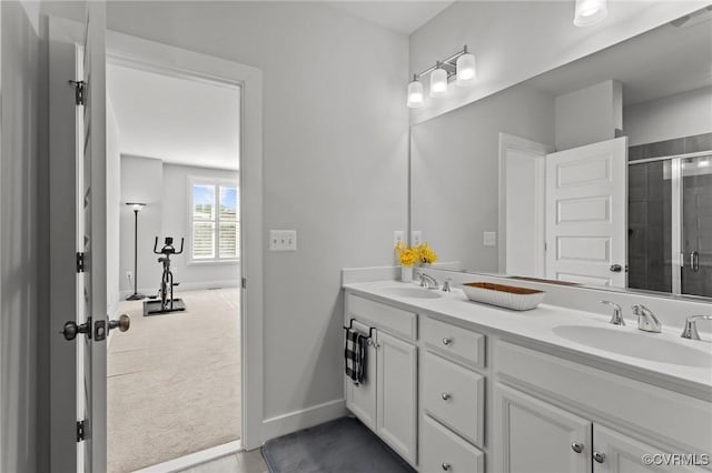 full bathroom with double vanity, a shower stall, baseboards, and a sink