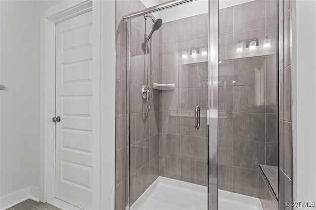 bathroom with a shower stall and baseboards