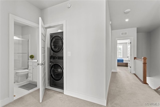 clothes washing area featuring laundry area, carpet floors, stacked washer / dryer, visible vents, and baseboards