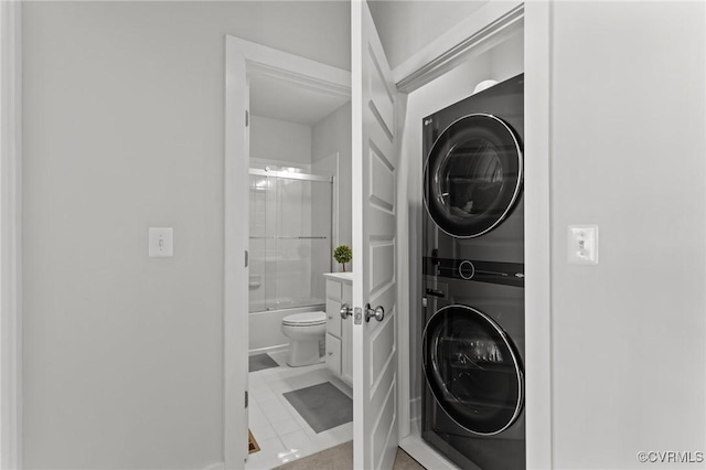 laundry room with stacked washing maching and dryer, laundry area, and tile patterned floors