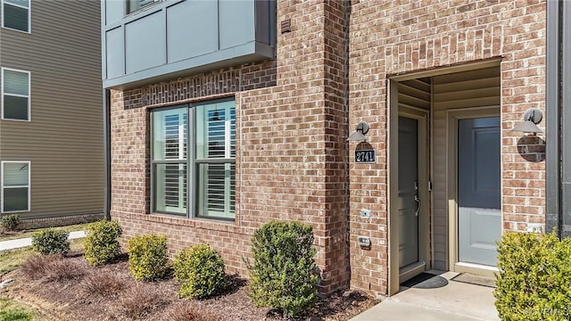 doorway to property featuring a garage and brick siding