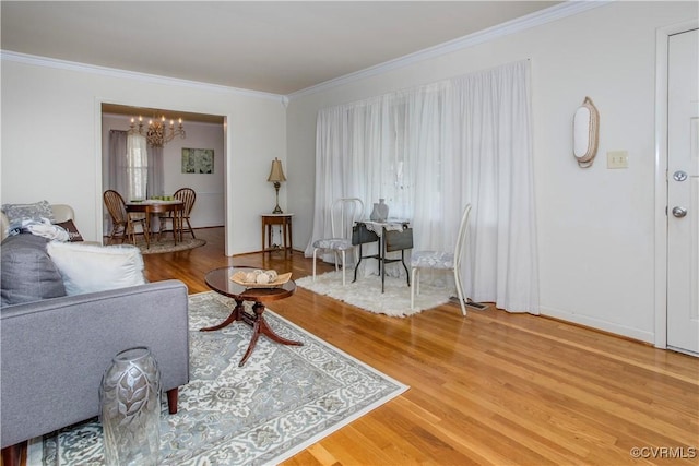 living room with ornamental molding, wood finished floors, and an inviting chandelier