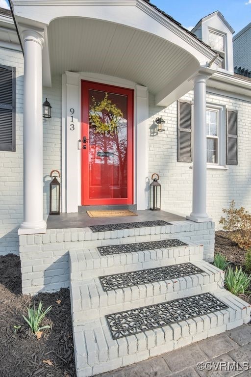 doorway to property featuring brick siding and a porch