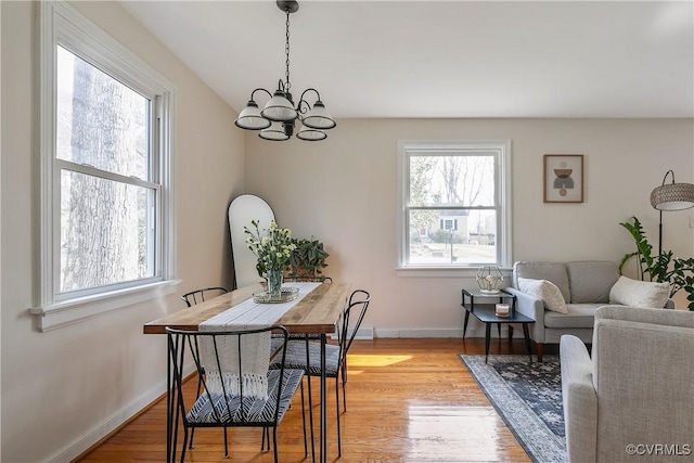 dining room with light wood-style floors, plenty of natural light, baseboards, and a chandelier