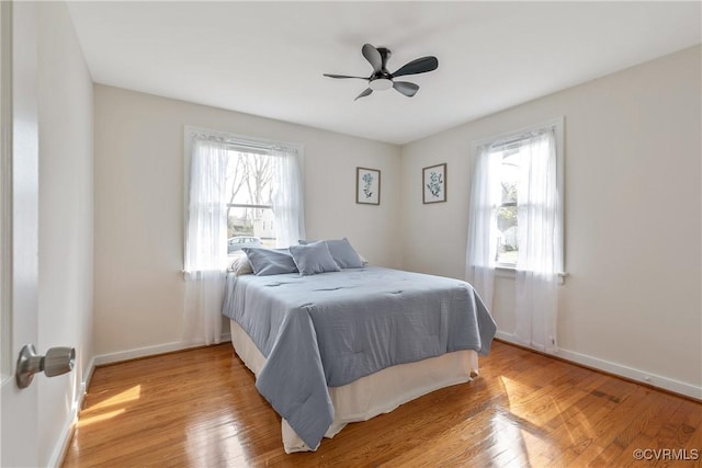 bedroom with multiple windows, wood finished floors, and baseboards