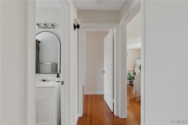 hallway with a sink and wood finished floors