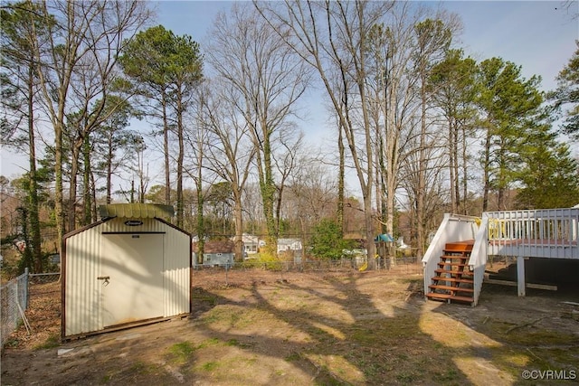 view of yard with an outbuilding, stairway, a storage shed, fence, and a deck