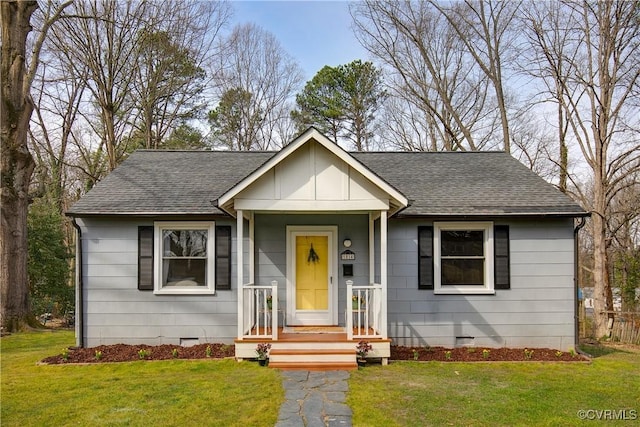 view of front of home with a shingled roof, crawl space, and a front lawn