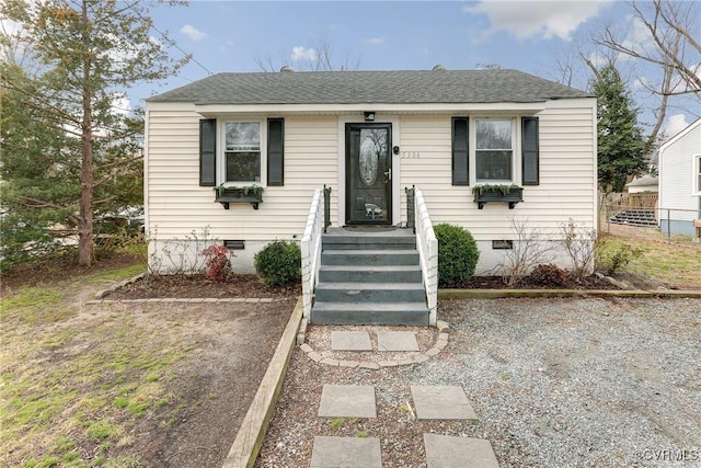 bungalow-style home with crawl space, roof with shingles, and fence