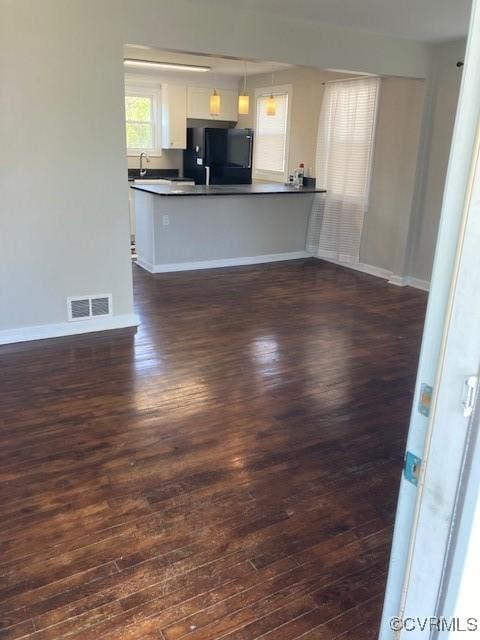 unfurnished living room featuring baseboards, dark wood finished floors, visible vents, and a sink