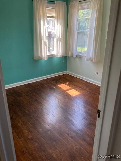 empty room with baseboards and dark wood finished floors
