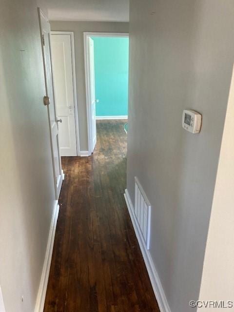 hall featuring baseboards, visible vents, and dark wood finished floors