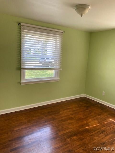 empty room with dark wood-type flooring and baseboards